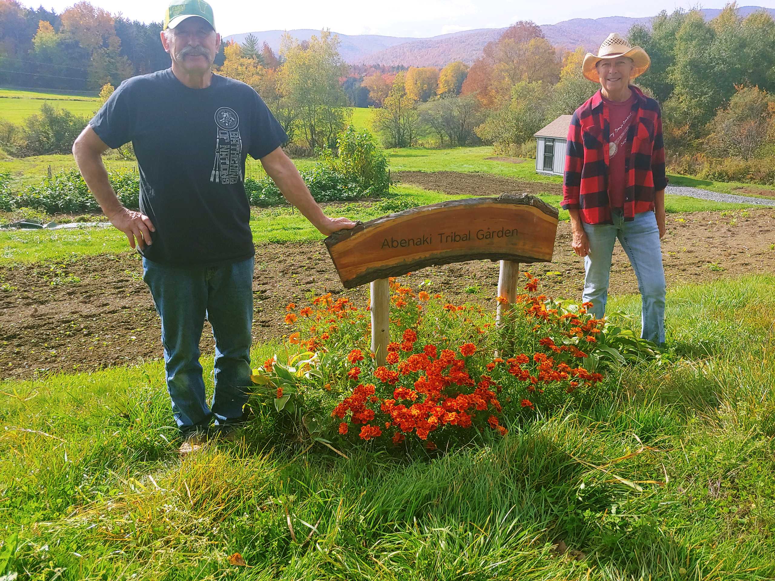 Koas Chief Shirly Hook with Doug Bent at Tribal Garden in Braintree Vermont - posing by tribal garden sign